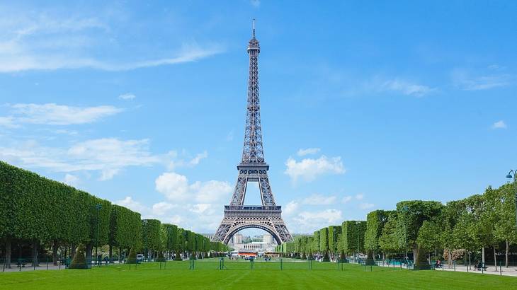 The Eiffel Tower with grass and trees in front of it on a clear day