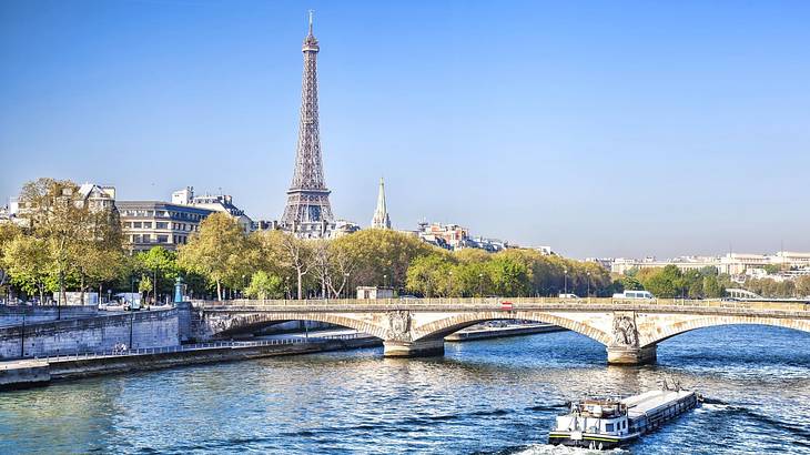 A boat on the water with a bridge and the Eiffel Tower in front of it