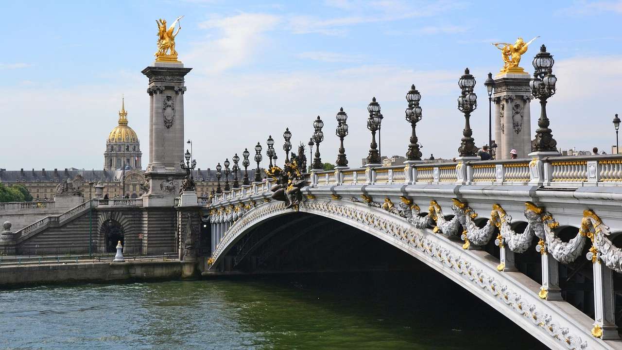 A bridge with gold statues on it and a river flowing below it