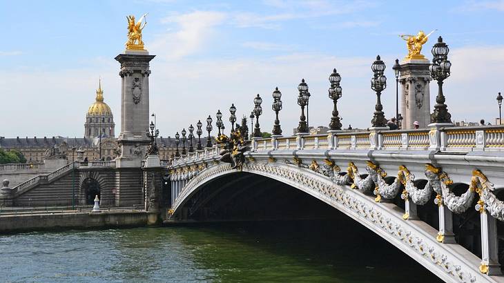 A bridge with gold statues on it and a river flowing below it