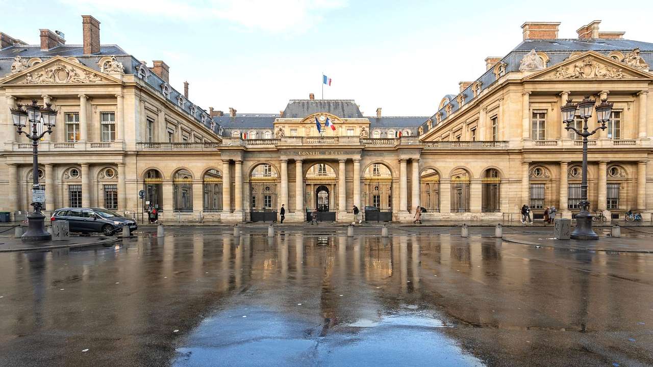 A French mansion building with a street in front of it after the rain