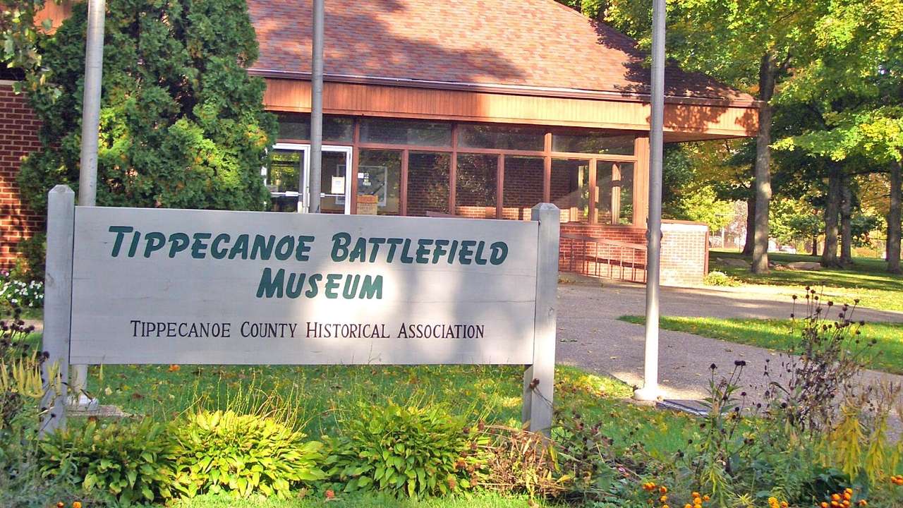A brick building with a sign in front of it that says "Tippecanoe Battlefield Museum"