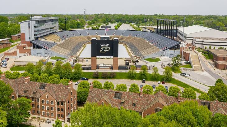 A football stadium with greenery and brick houses surrounding it