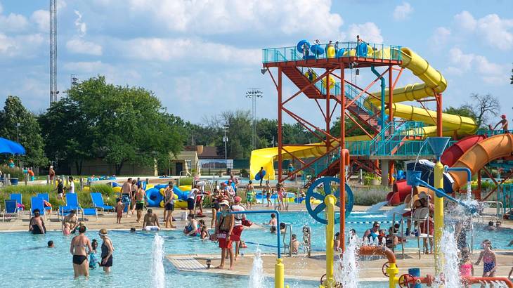 A waterpark with people in a pool and colorful waterslides