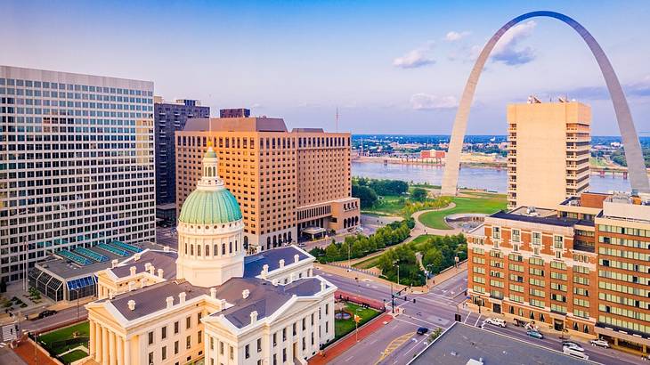 A city view with an arch structure and other buildings and a river in the distance