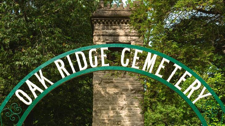 A green arch sign that says "Oak Ridge Cemetery" with trees behind it