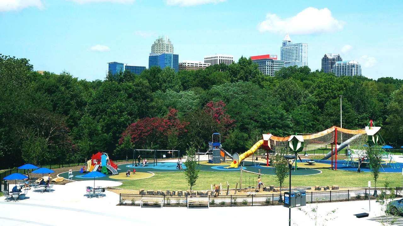 A park with a colorful kids' playground and trees and buildings in the background