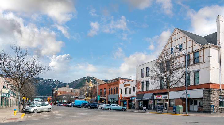 A rural city street with cars and buildings next to a hills