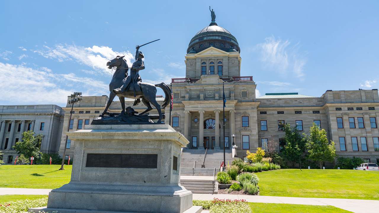 A rectangular domed building with a man on a horse statue in front