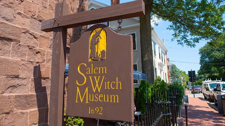 A wooden sign that says "Salem Witch Museum 1692" and has a witch silhouette on it