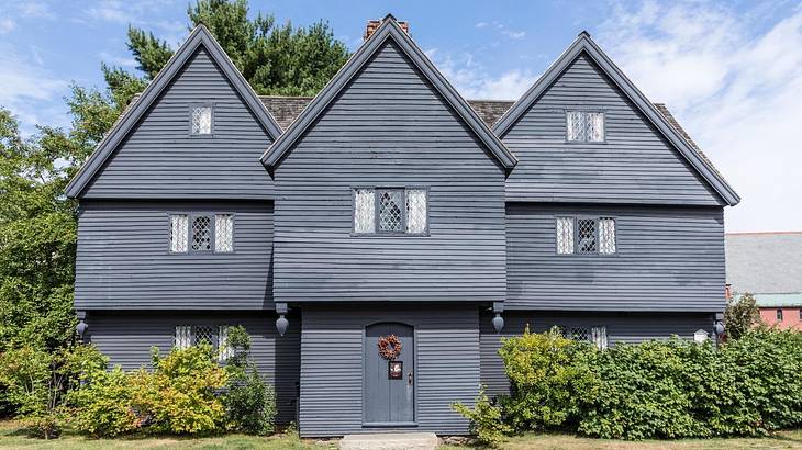 A black wooden house with greenery in front of it under a blue sky