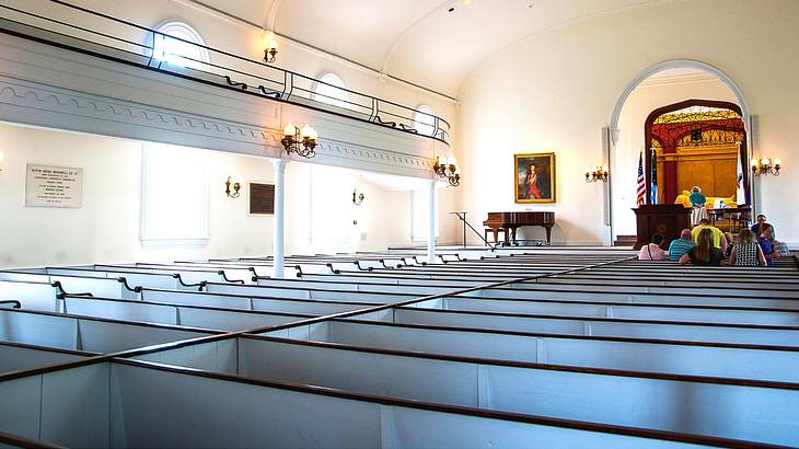 The inside of a chapel with white pews and people at the front during a service