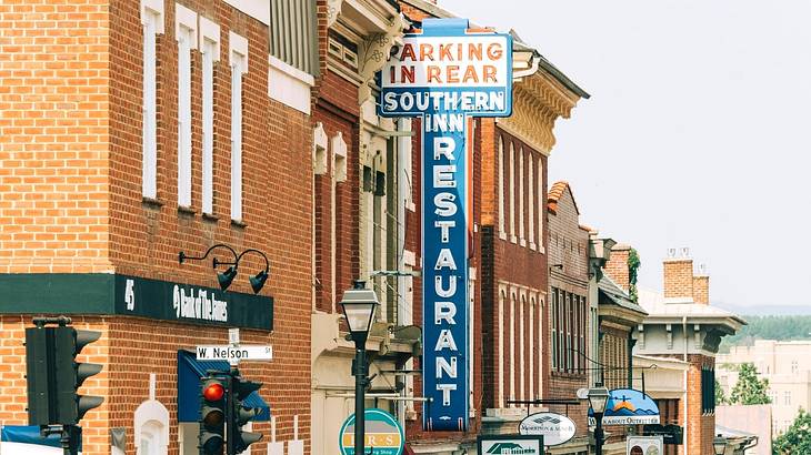 A brick building with a blue sign in the shape of a cross that says "Southern Inn"