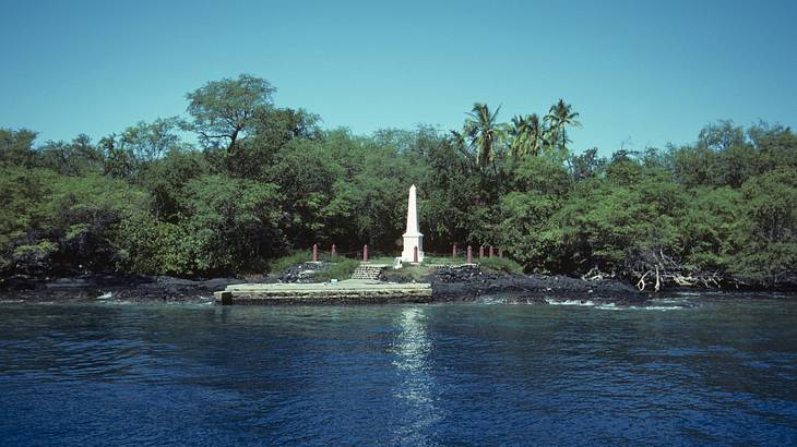 White monument and trees on the coastline