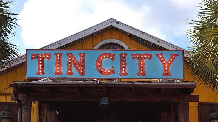 A wooden building with an illuminated "Tin City" sign on it