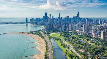 An aerial view of Chicago with water, sand, a park, and skyscrapers