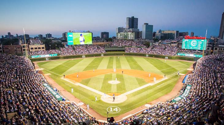 Fans watching a baseball game at a baseball field with a city skyline in the back Fans watching a baseball game at a baseball field with a city skyline in the back