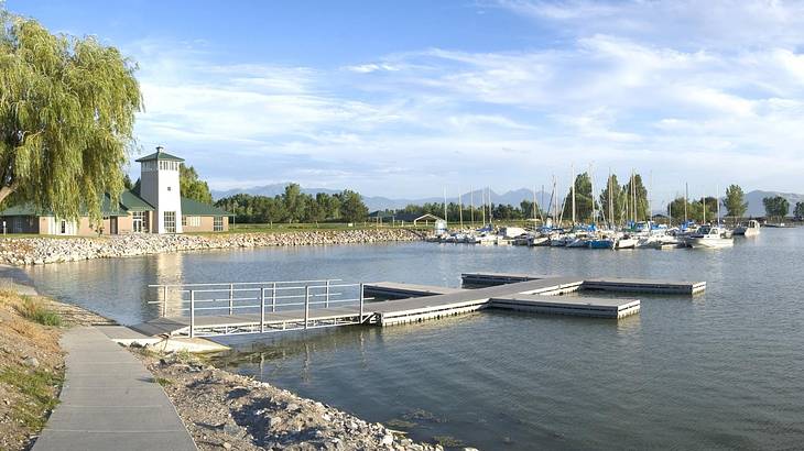 A lake with a boat dock and a path and trees surrounding it A lake with a boat dock and a path and trees surrounding it