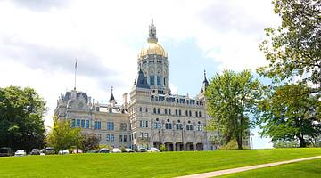A Gothic-style building with a gold-domed roof, green grass, and trees