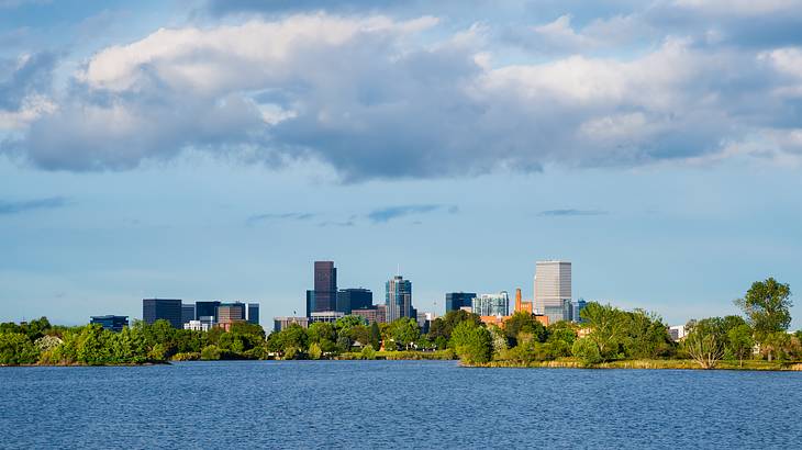 A lake with green trees and buildings on the shore A lake with green trees and buildings on the shore