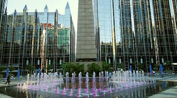An urban square with a water feature and tall mirrored buildings