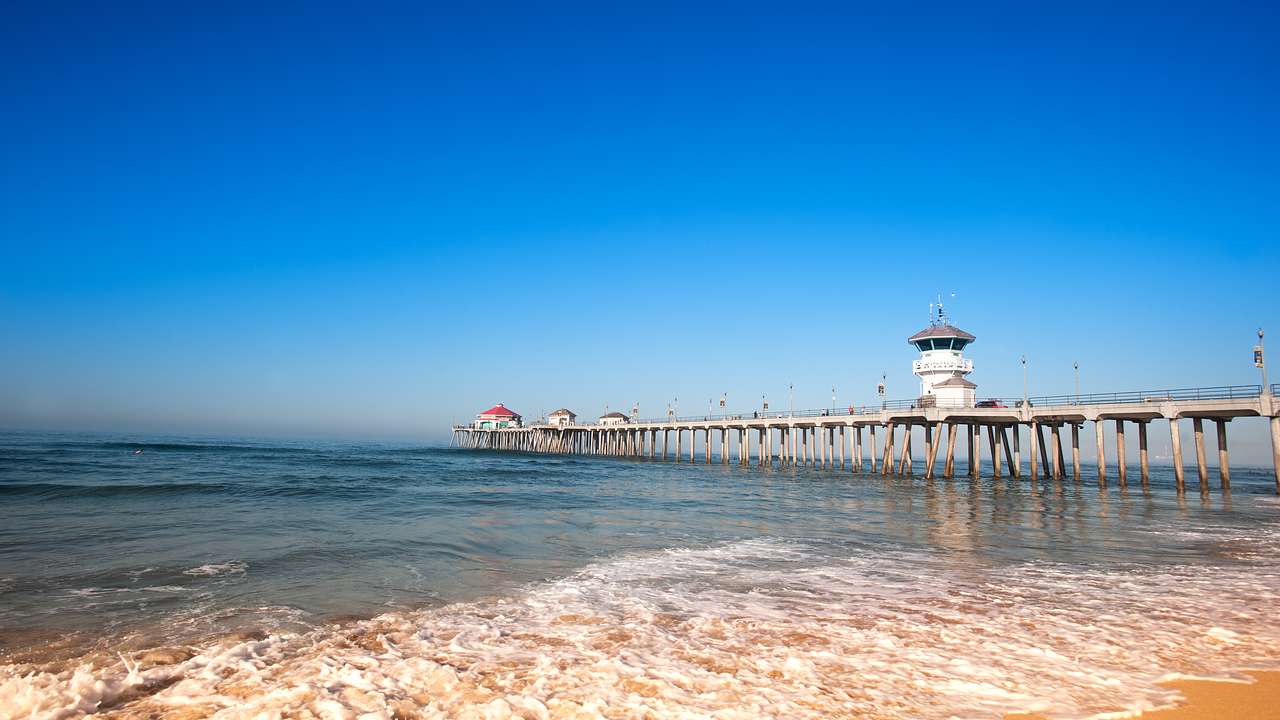 A long pier stretching into the ocean, with seawater and sand to the side
