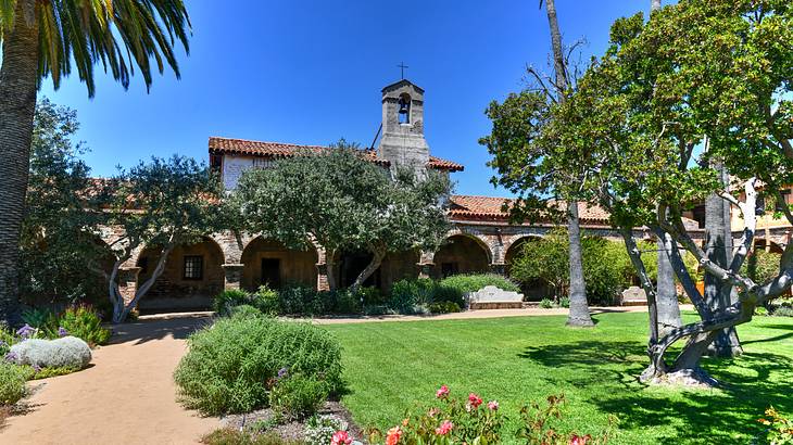 A stone mission building with a green garden in front of it