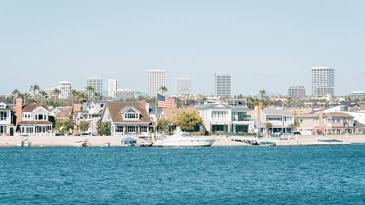 Blue ocean water with a white sand shore and buildings in the background