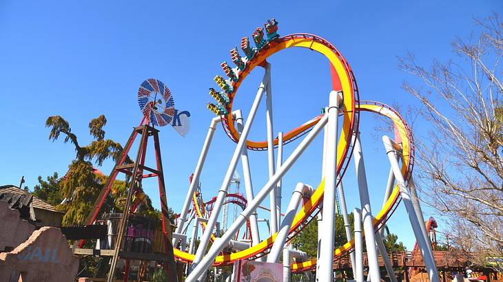 A red and yellow roller coaster with trees around it, under a blue sky