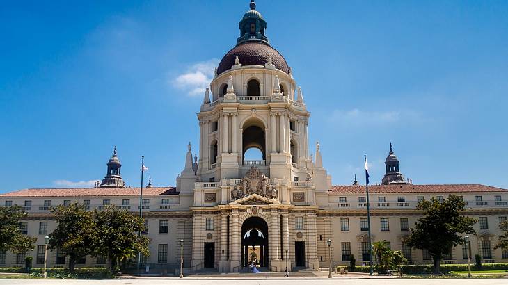 A city hall building with dome structure in the middle and trees in front