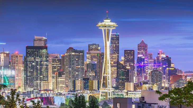 A skyline at night with illuminated buildings and an observation tower