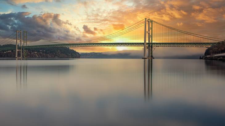 A bridge running across a body of water at sunset