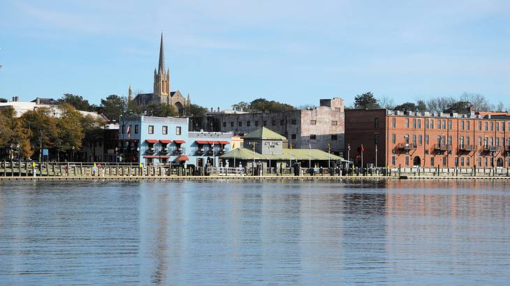 A town skyline with a river in front of it under a blue sky