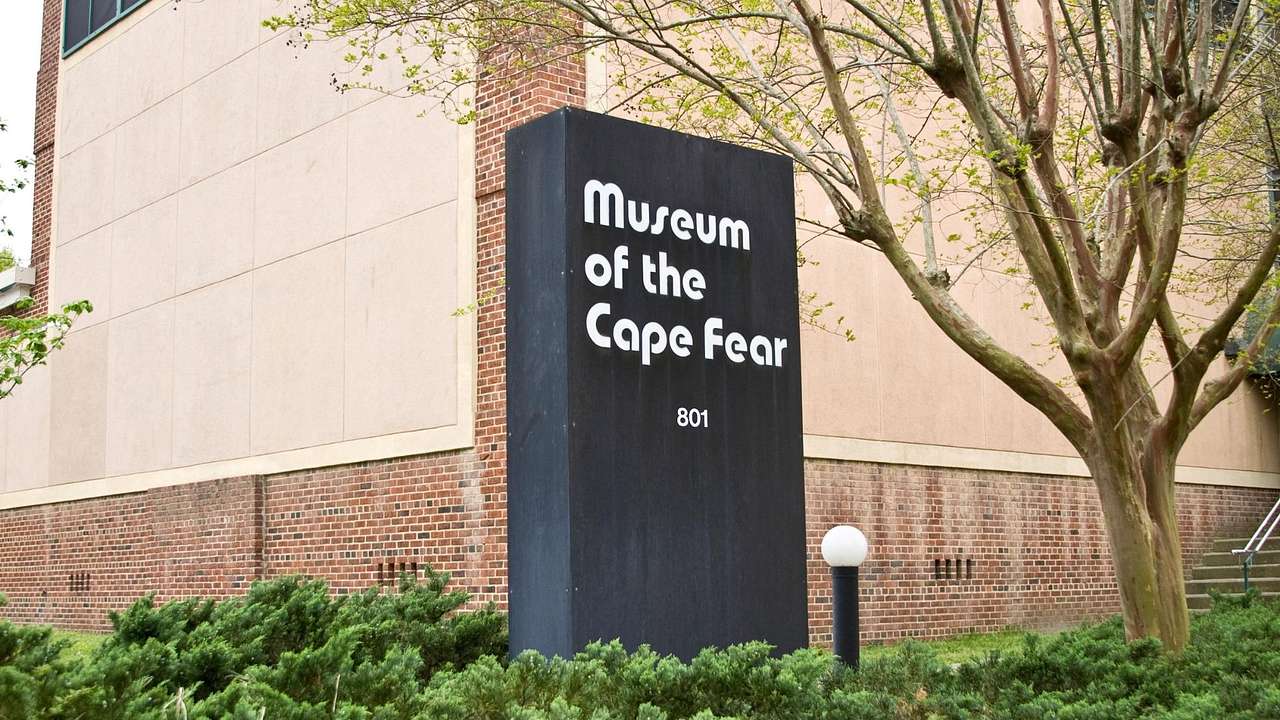 A black sign that says "Museum of the Cape Fear" in front of a building