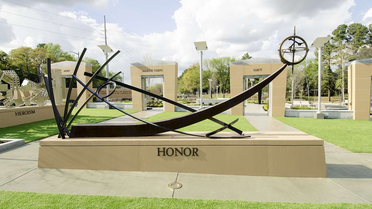 A sculpture that says "Honor" sitting on the grass with other sculptures behind it
