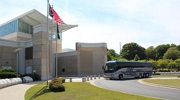 A building with a coach and flags in front of it and green grass surrounding