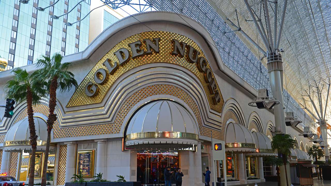 Gold and white casino building with words Golden Nugget on it and palms in front