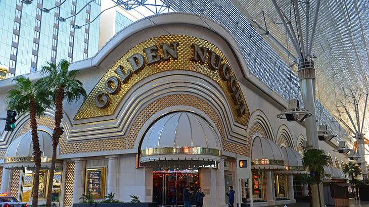 Gold and white casino building with words Golden Nugget on it and palms in front