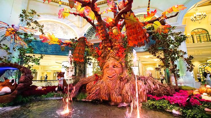 An indoor garden display with a fountain, colorful flowers, and fairytale tree