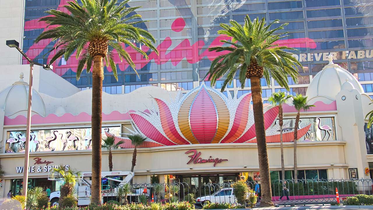 A hotel exterior with a pink lotus flower sculpture and signs saying flamingo