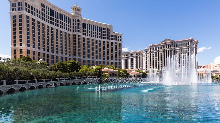 A large hotel building with a body of water and fountains in front