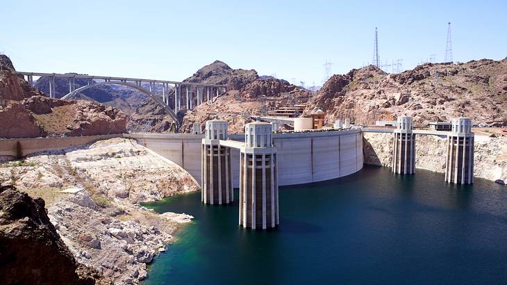 A dam with water in front and hills surrounding