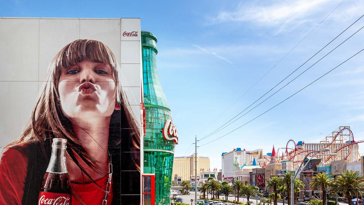 A mural of a woman holding a Coca-Cola bottle and a large Coca-Cola bottle replica