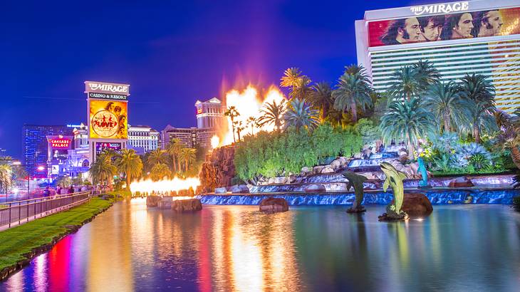 Reflections in a pool of water and a replica volcano erupting in the background