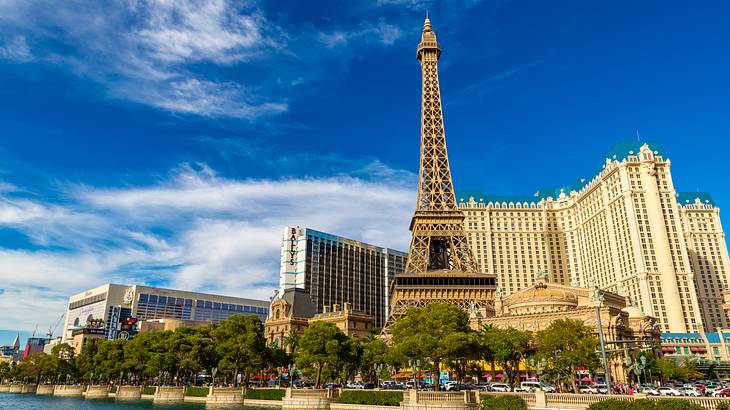 An Eiffel Tower Replica with buildings surrounding it and water in front of it