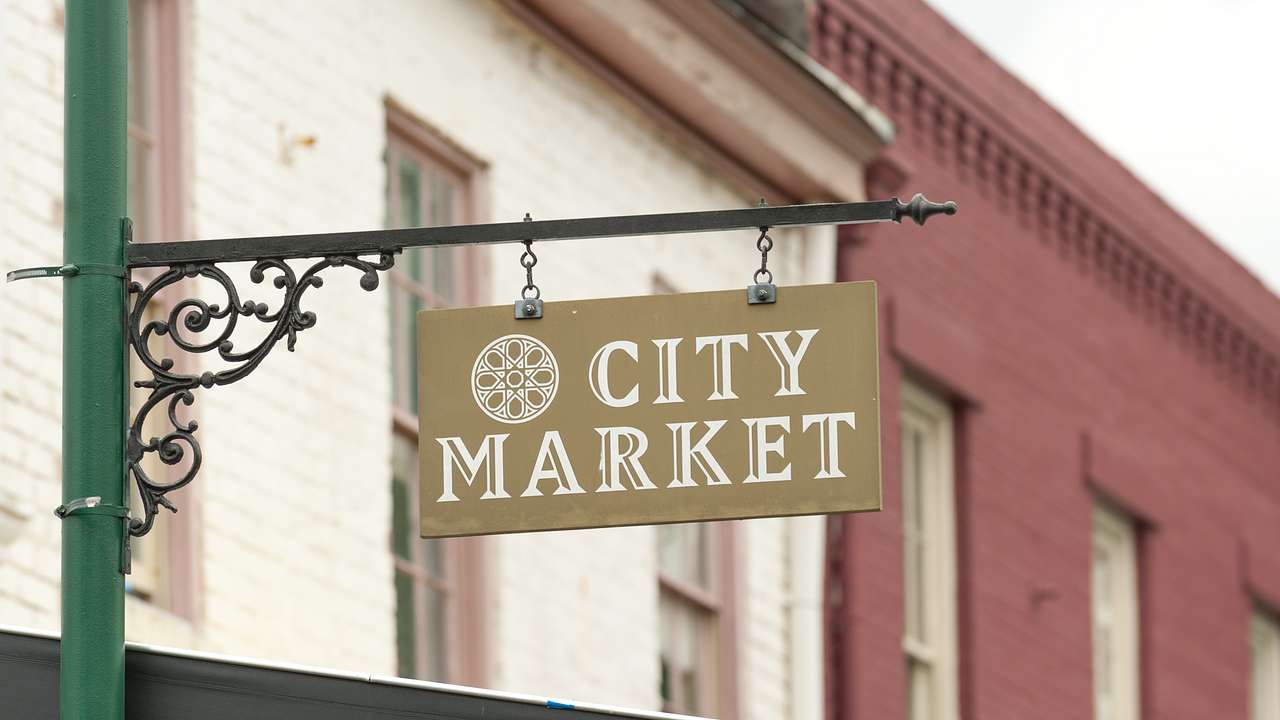 A green sign post in front of buildings with a sign that says City Market