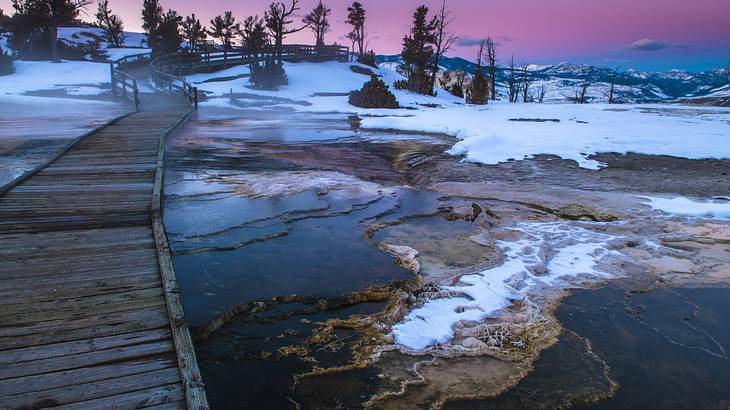 Pedestrian bridge over icy and snow-covered water with a purplish sky