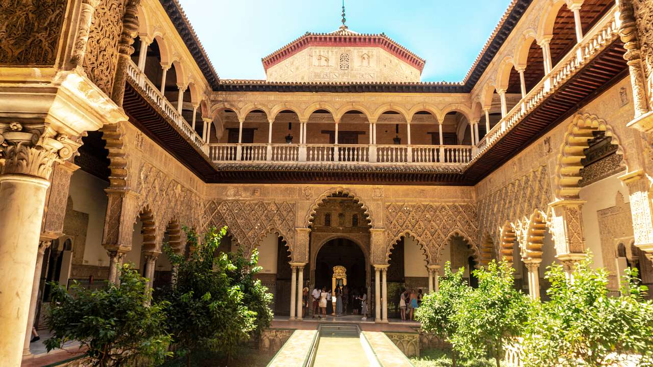 An interior courtyard framed by a u-shaped, two-floor palace with arched balconies