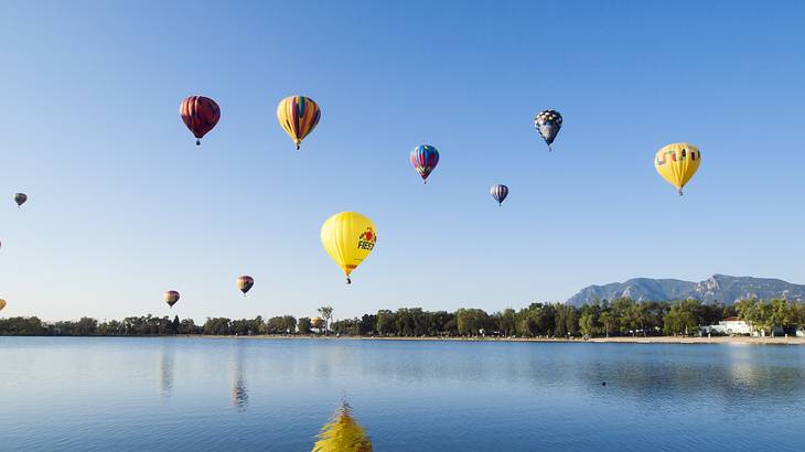 Colorful hot air balloons flying above a lake