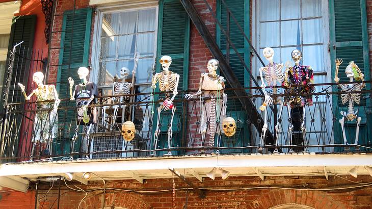 Balcony filled with "happy" skeletons brick building and windows with green shutters